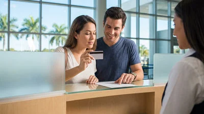 Close up of a person holding a credit card at a car hire counter in Miami