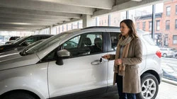 Person holding car keys next to a modern car rental vehicle parked on a New York street