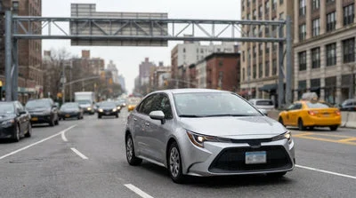 A car rental driving in heavy traffic on a busy street in New York City with yellow cabs and skyscrapers in the background